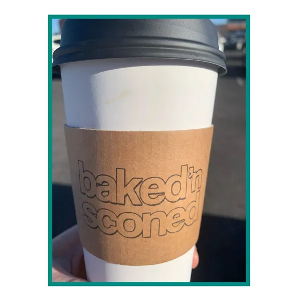 A baked'nsconed to-go coffee cup with a kraft sleeve