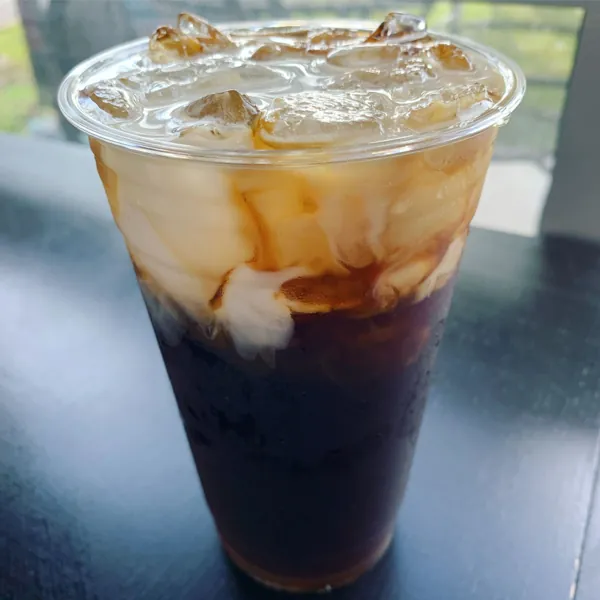 Iced coffee with cream swirling through house cold brew