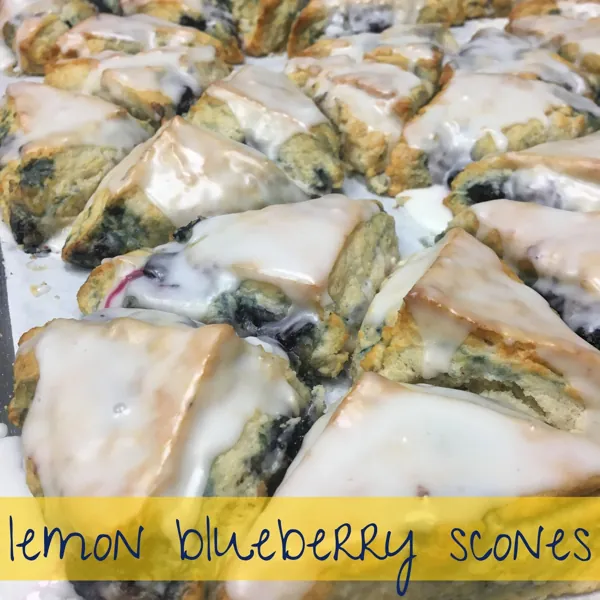 Lemon blueberry scones with a white glaze drizzle on a sheet tray
