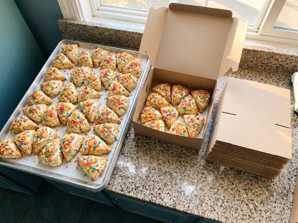 A sheet tray of scones being packed into bakery boxes